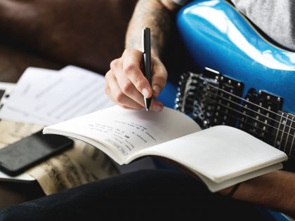 Man writing a song while holding the guitar